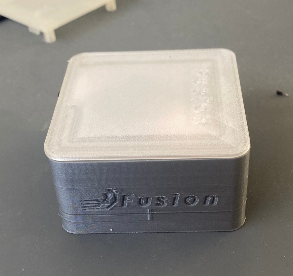 The working Ghost Logger prototype on a workbench: a 3D-printed grey body with a frosted clear lid and the Fusion logo